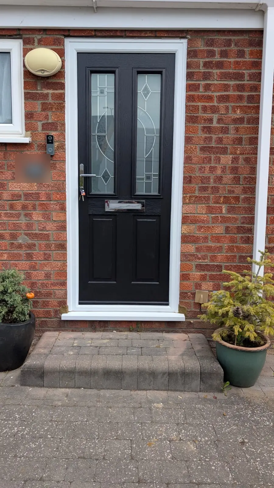 Black Whitmore composite front door with a white frame and Modena glass, fitted to a red brick house in Chelmsford