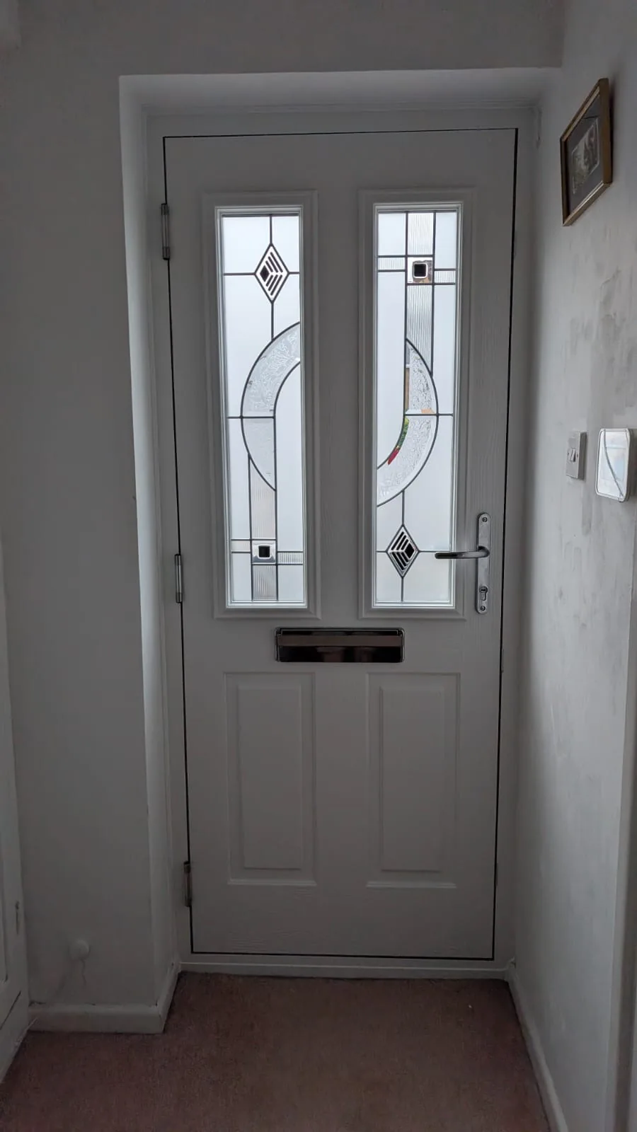The same Whitmore composite door viewed from inside the hallway, showing the white internal face and Modena glazing