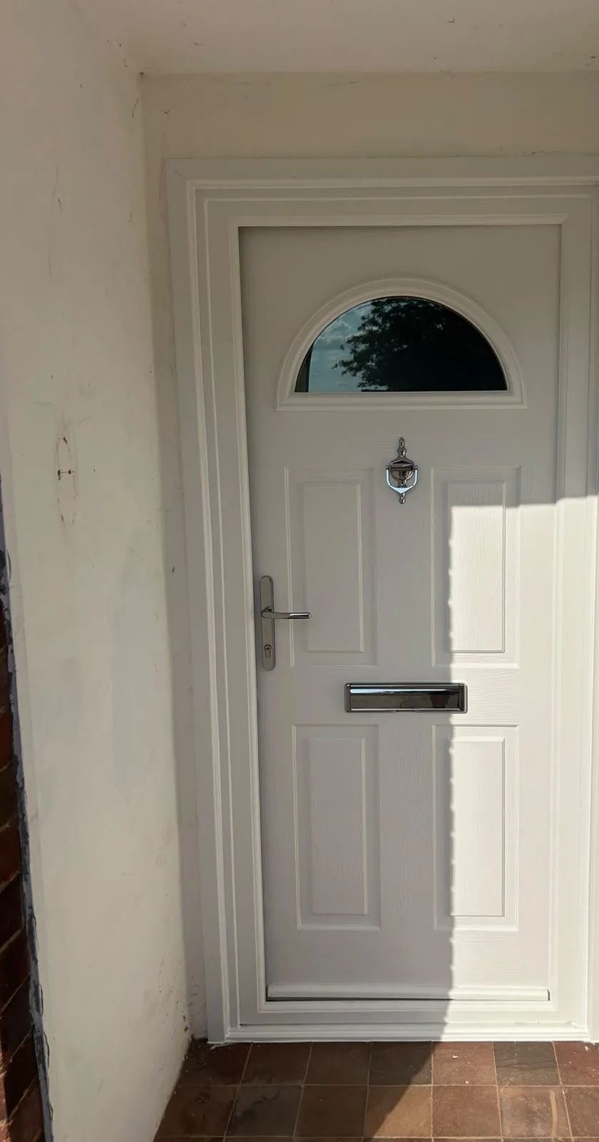 New white composite front door with arched glass panel, seen from the porch
