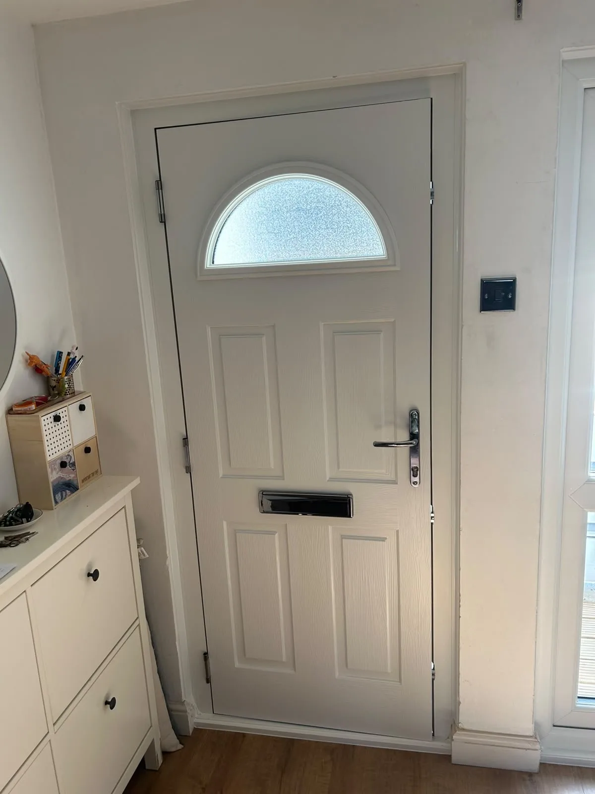 White composite front door from inside the hallway, showing the arched glass panel
