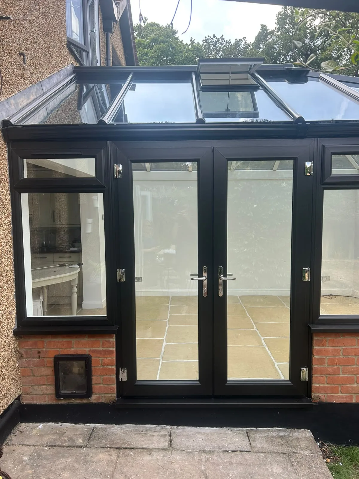 Black French doors from outside, looking through to the kitchen beyond