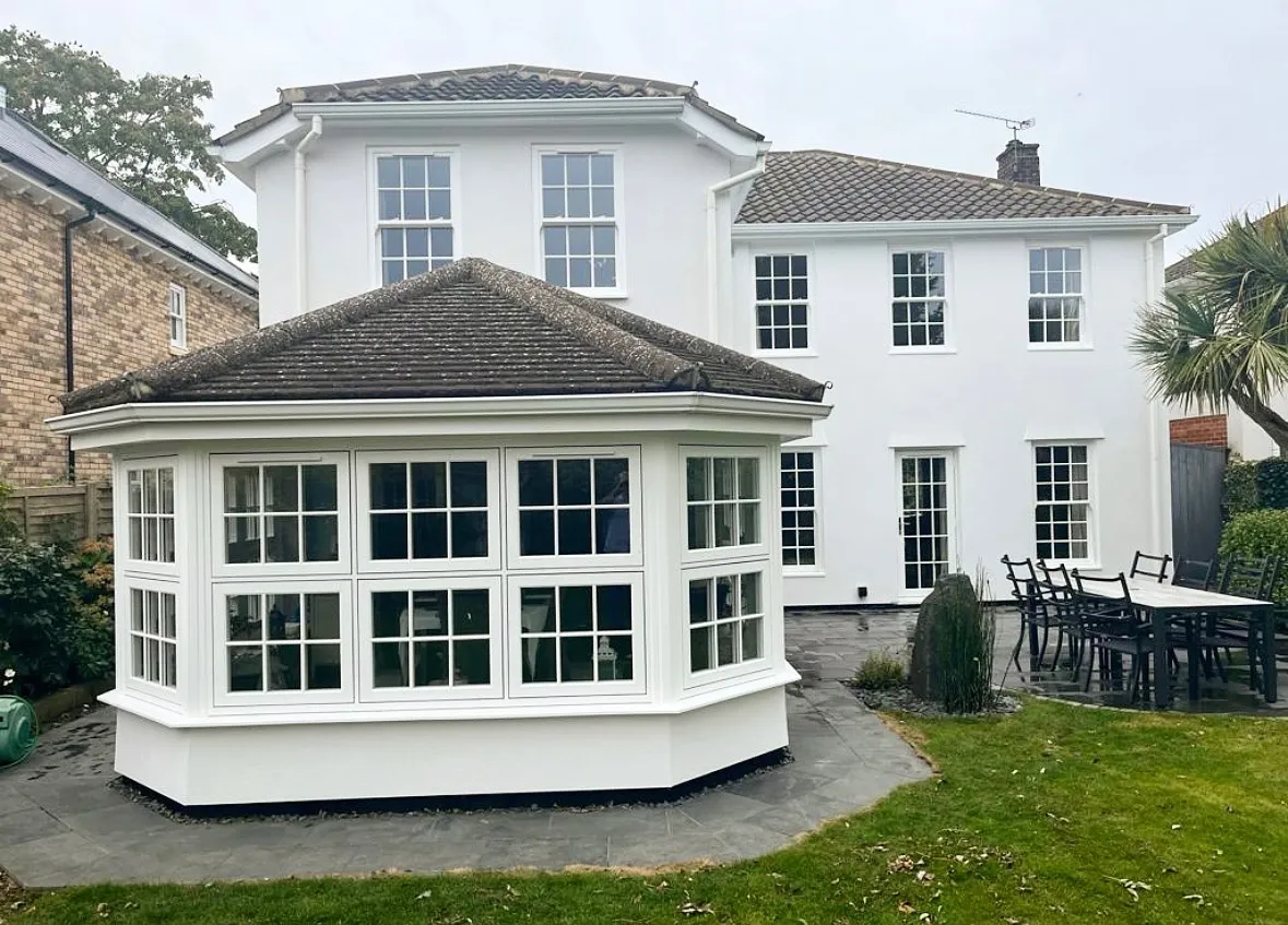 White uPVC Georgian bar windows on a single-storey bay beside a large white house