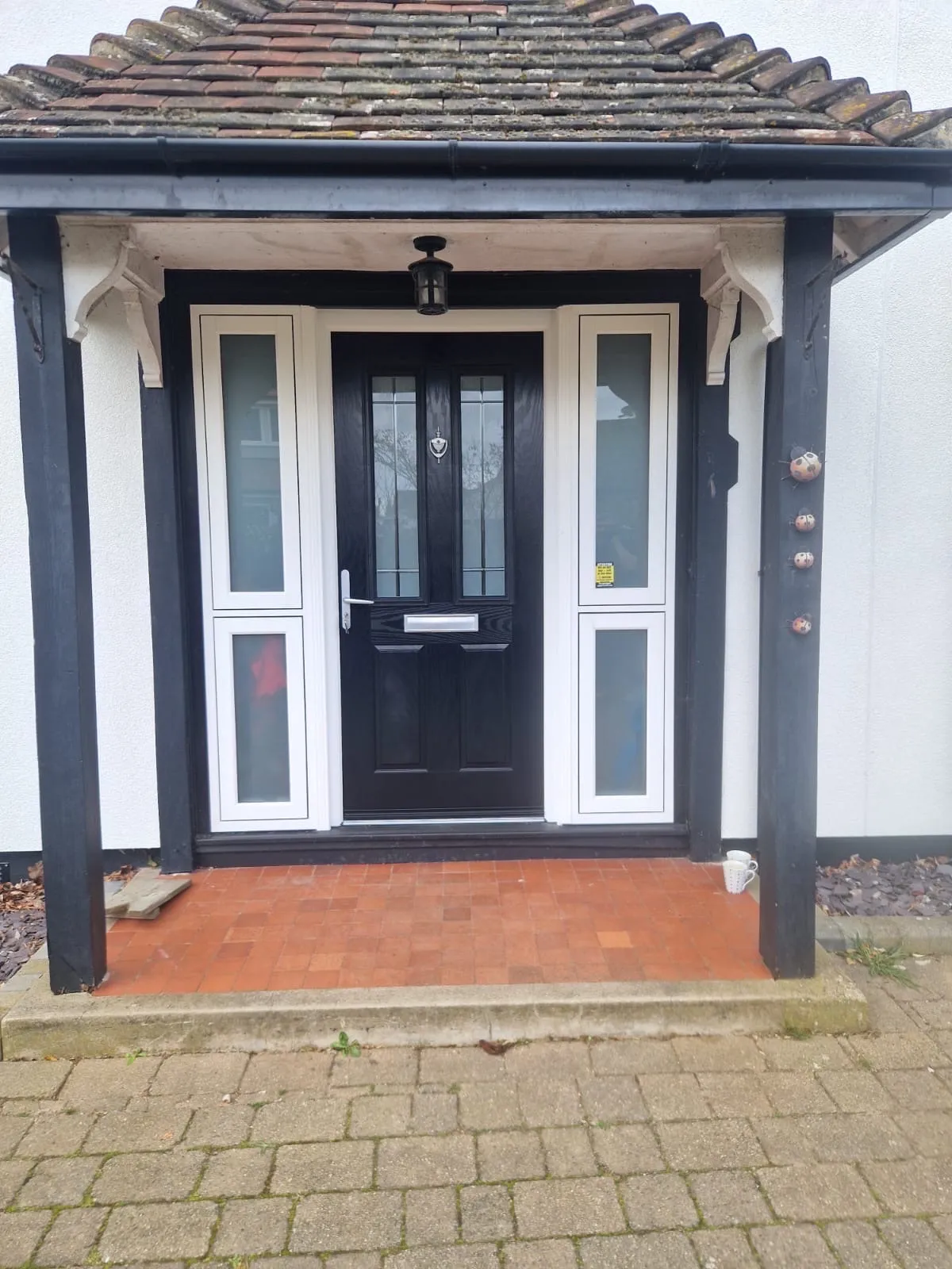 Black composite front door with leaded glass, chrome knocker and letterplate, between white glazed side panels